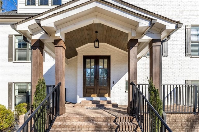 doorway to property with brick siding, covered porch, and french doors