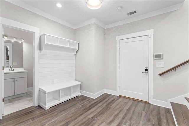 mudroom featuring wood finished floors, baseboards, visible vents, a sink, and crown molding