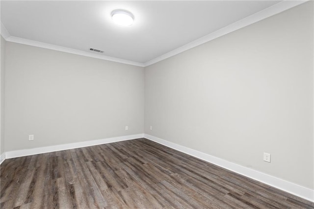 spare room with dark wood-style floors, baseboards, visible vents, and ornamental molding