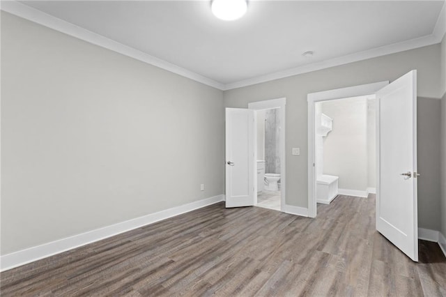 unfurnished bedroom with baseboards, ensuite bath, wood finished floors, and crown molding