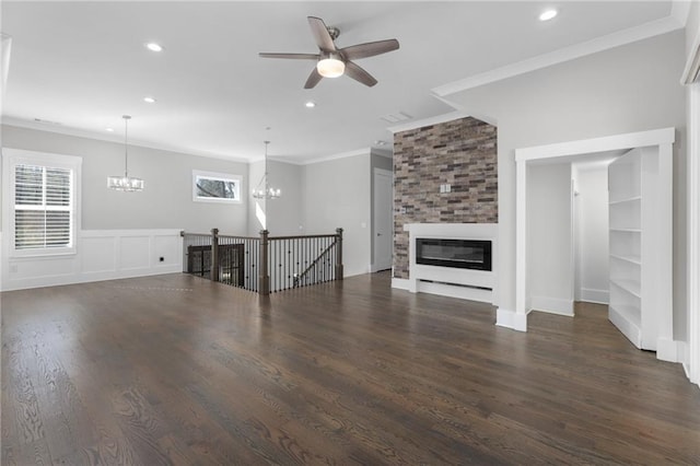 unfurnished living room with ceiling fan with notable chandelier, recessed lighting, a large fireplace, crown molding, and dark wood-style flooring