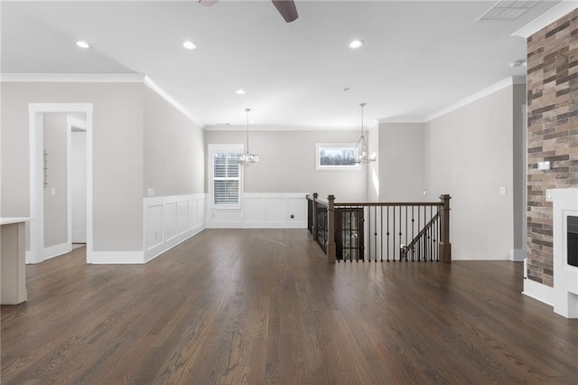 unfurnished room with crown molding, a wainscoted wall, recessed lighting, a fireplace, and dark wood-style flooring