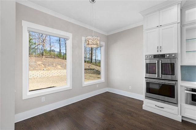 kitchen featuring baseboards, dark wood finished floors, ornamental molding, stainless steel double oven, and white cabinetry