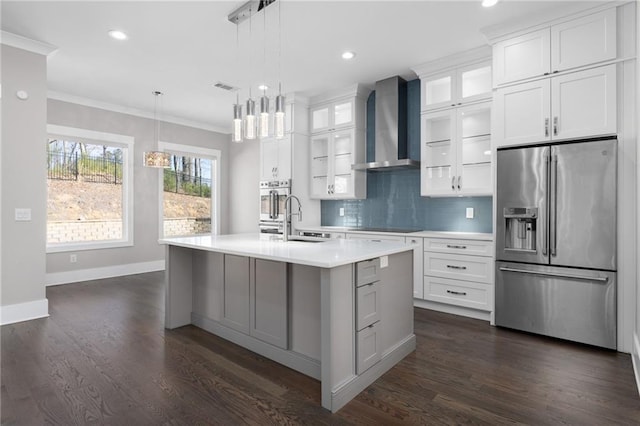 kitchen with ornamental molding, wall chimney range hood, backsplash, stainless steel fridge, and light countertops