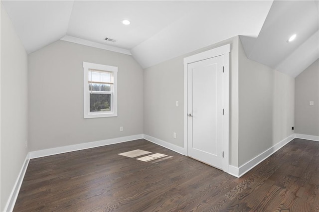 additional living space with visible vents, baseboards, dark wood-style flooring, and vaulted ceiling