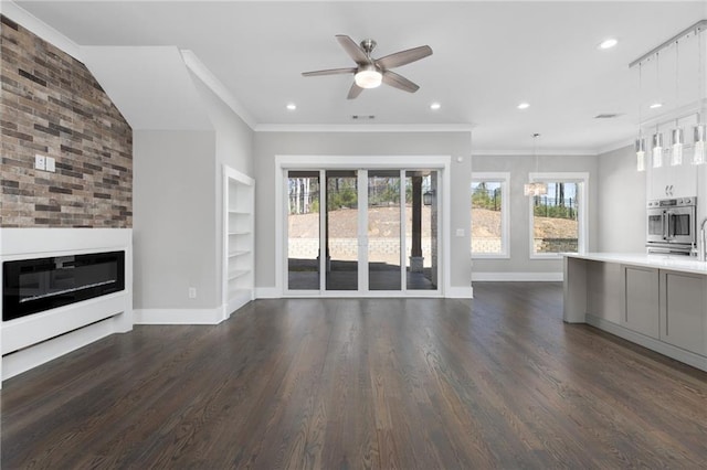 unfurnished living room with dark wood finished floors, crown molding, built in shelves, and baseboards