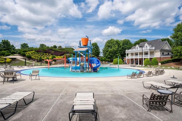 view of pool featuring a playground, a patio, and a water slide