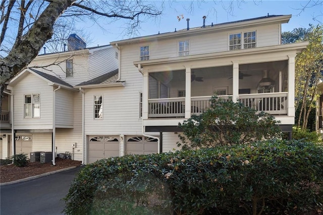 rear view of house featuring a sunroom, cooling unit, and a garage