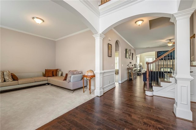 entryway featuring dark wood-type flooring, ceiling fan, crown molding, and ornate columns