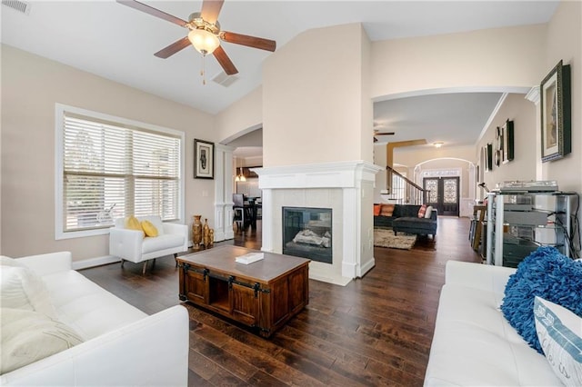 living room featuring a tiled fireplace, vaulted ceiling, dark wood-type flooring, and ceiling fan