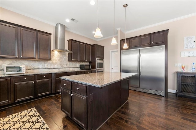 kitchen with dark brown cabinetry, decorative light fixtures, a center island, black appliances, and wall chimney range hood