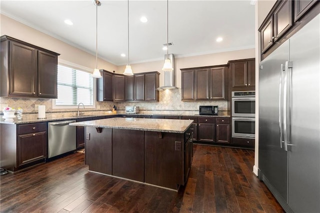 kitchen with hanging light fixtures, dark brown cabinets, stainless steel appliances, a center island, and light stone counters