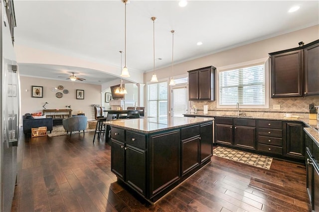 kitchen with pendant lighting, sink, dark hardwood / wood-style flooring, a center island, and light stone countertops