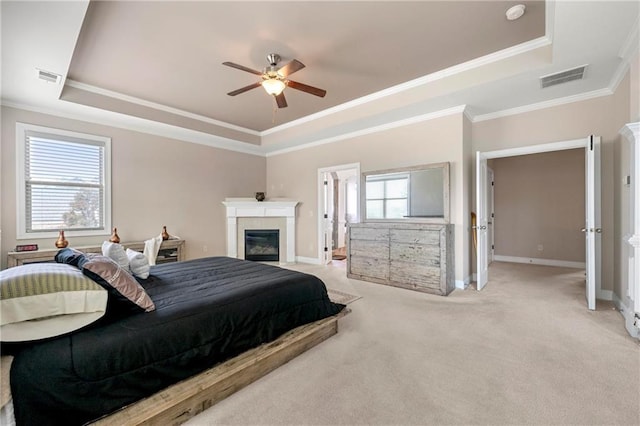 bedroom featuring multiple windows, a tray ceiling, ornamental molding, and light colored carpet