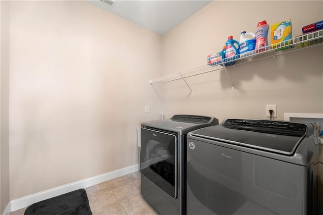 clothes washing area with light tile patterned floors and washing machine and clothes dryer