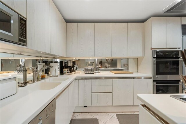 kitchen featuring light tile patterned floors, light countertops, appliances with stainless steel finishes, and a sink