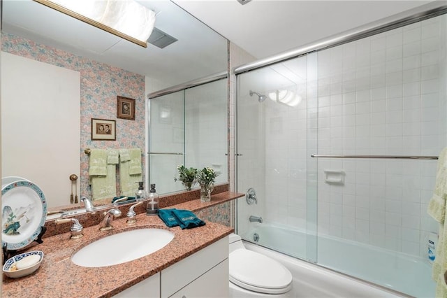 bathroom with enclosed tub / shower combo, vanity, toilet, and wallpapered walls
