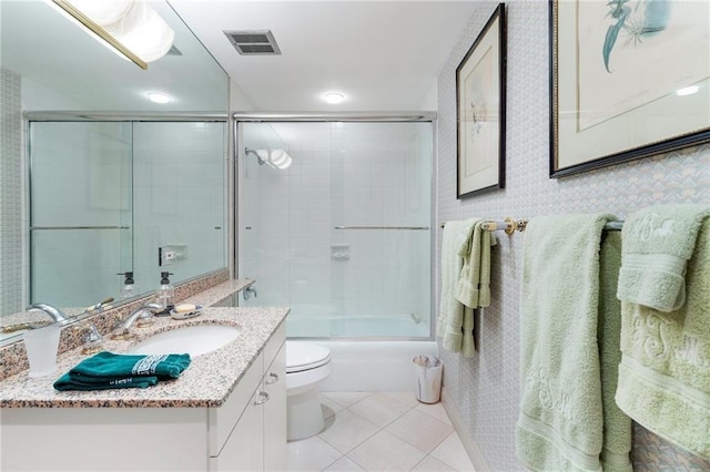 full bathroom featuring bath / shower combo with glass door, visible vents, toilet, vanity, and tile patterned floors