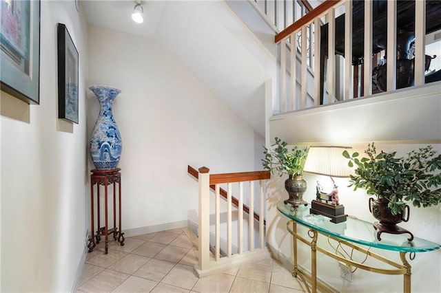 stairway with baseboards, vaulted ceiling, and tile patterned floors