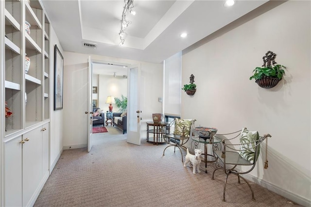 corridor featuring a tray ceiling, recessed lighting, visible vents, light carpet, and track lighting
