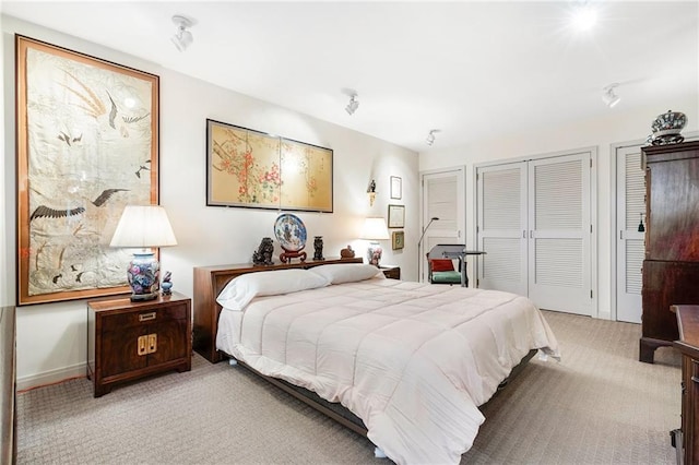 bedroom with light carpet and two closets