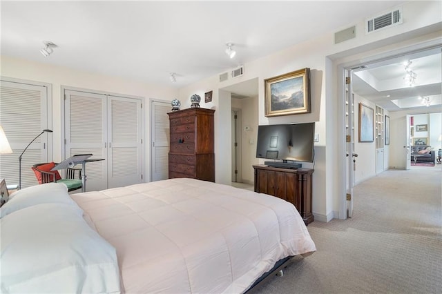 bedroom featuring light carpet, baseboards, visible vents, and two closets