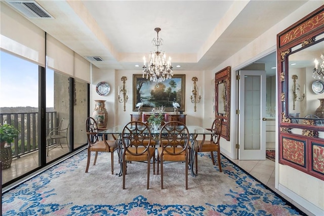 dining room with a tray ceiling, tile patterned flooring, visible vents, and an inviting chandelier