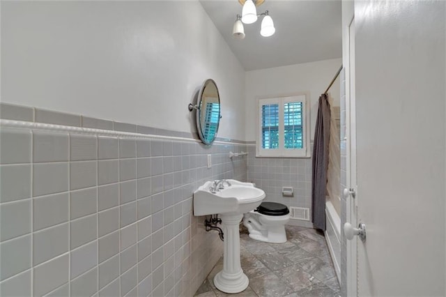 1618 Mason Mill Rd NE, Atlanta, GA 30329 - bathroom featuring shower / tub combo with curtain, tile walls, and a wainscoted wall