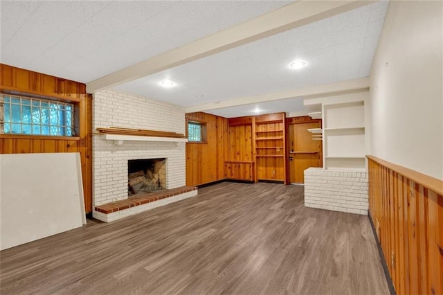 1618 Mason Mill Rd NE, Atlanta, GA 30329 - unfurnished living room featuring wooden walls, wood finished floors, a brick fireplace, and beam ceiling
