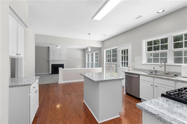 7000 Foxberry Ln, Roswell, GA 30075 - kitchen with stainless steel dishwasher, a kitchen island, a textured ceiling, open floor plan, and white cabinets