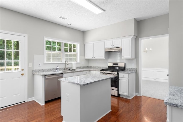 7000 Foxberry Ln, Roswell, GA 30075 - kitchen featuring appliances with stainless steel finishes, under cabinet range hood, white cabinets, plenty of natural light, and a textured ceiling