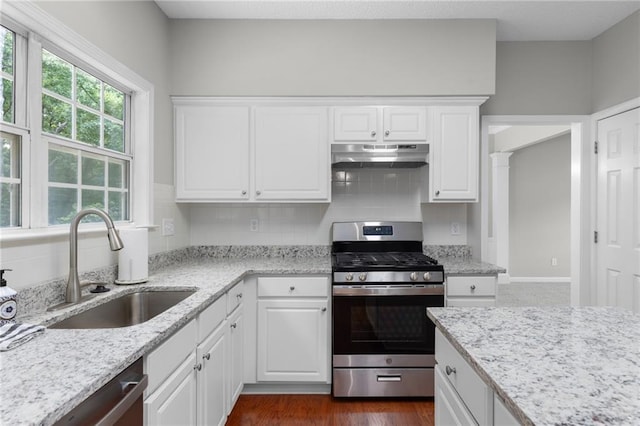 7000 Foxberry Ln, Roswell, GA 30075 - kitchen featuring appliances with stainless steel finishes, under cabinet range hood, white cabinetry, decorative backsplash, and light stone counters