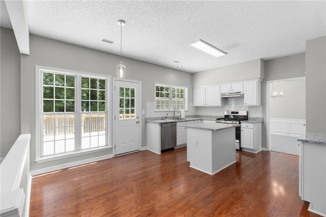7000 Foxberry Ln, Roswell, GA 30075 - kitchen featuring stainless steel appliances, under cabinet range hood, white cabinetry, dark wood-style flooring, and a kitchen island