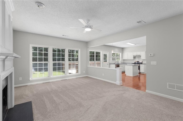 7000 Foxberry Ln, Roswell, GA 30075 - unfurnished living room featuring light colored carpet, ceiling fan, a fireplace with flush hearth, and a textured ceiling