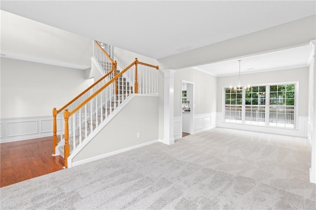7000 Foxberry Ln, Roswell, GA 30075 - unfurnished living room featuring a decorative wall, a chandelier, wainscoting, carpet floors, and stairway