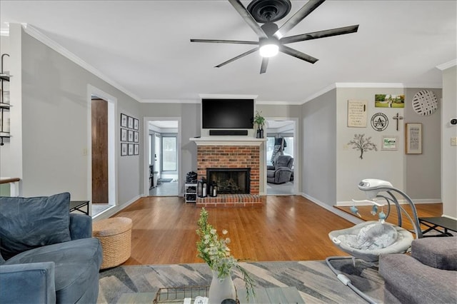 living room with a fireplace, light hardwood / wood-style flooring, ceiling fan, and ornamental molding