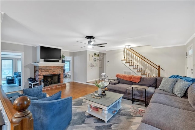 living room featuring hardwood / wood-style flooring, a fireplace, ceiling fan, and ornamental molding