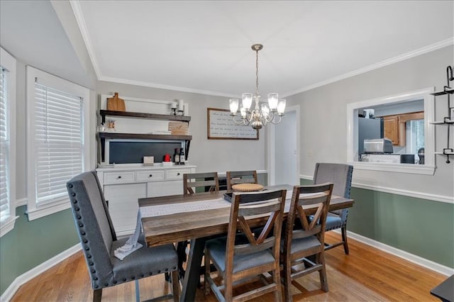 dining space featuring crown molding, light hardwood / wood-style flooring, and a notable chandelier