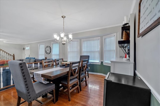 dining space with hardwood / wood-style floors, an inviting chandelier, and ornamental molding