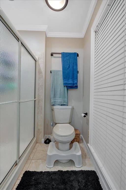 bathroom featuring toilet, a shower with door, tile patterned flooring, and ornamental molding