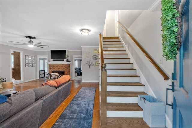 stairs with ceiling fan, crown molding, a fireplace, hardwood / wood-style floors, and plenty of natural light