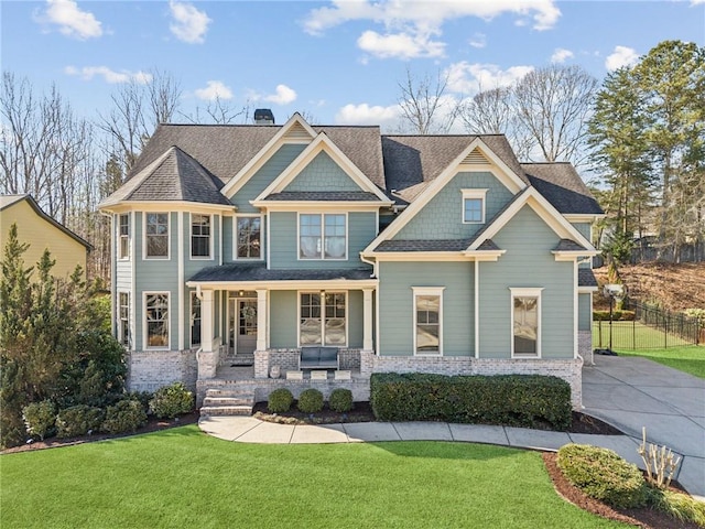 view of front of home with a front yard, covered porch, brick siding, and a chimney