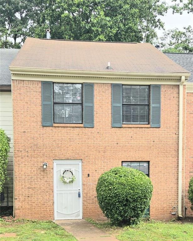 view of front of home featuring roof with shingles and brick siding