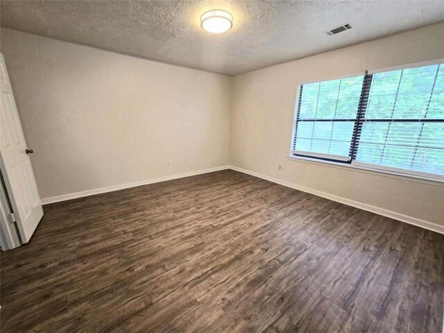 unfurnished room featuring dark wood finished floors, baseboards, and a textured ceiling