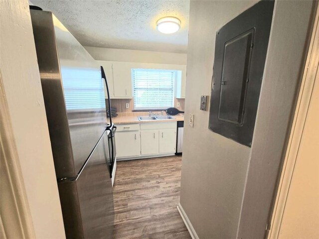 hall featuring a sink, electric panel, wood finished floors, a textured ceiling, and baseboards