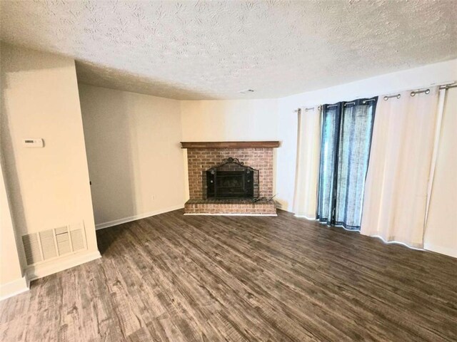 unfurnished living room featuring wood finished floors, a fireplace, a textured ceiling, and baseboards