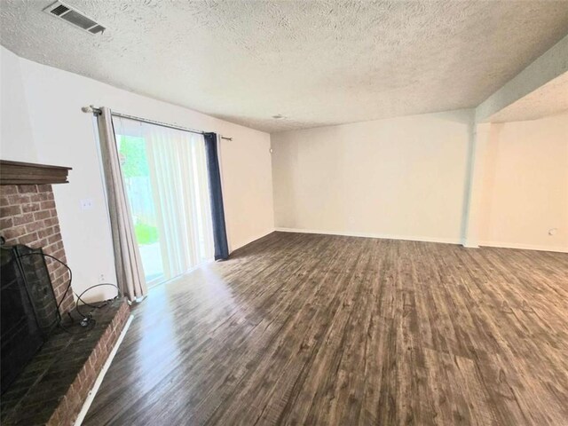 unfurnished living room featuring wood finished floors, a textured ceiling, and baseboards