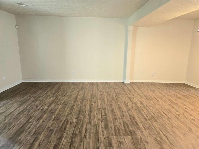 spare room featuring dark wood-style flooring, baseboards, and a textured ceiling