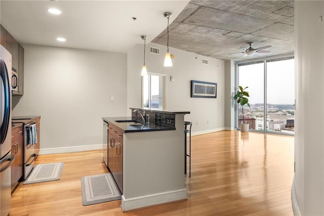 44 Peachtree Pl NE Unit 1824, Atlanta, GA 30309 - kitchen with a sink, stainless steel appliances, light wood-style flooring, dark countertops, and expansive windows