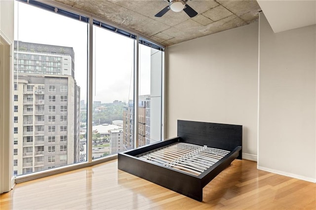 44 Peachtree Pl NE Unit 1824, Atlanta, GA 30309 - bedroom with wood finished floors, floor to ceiling windows, a view of city, baseboards, and a ceiling fan